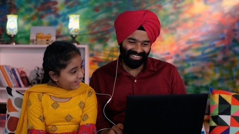 A cute little girl and her middle-aged father watching an online video / cartoon together - single father, single parent, helicopter parenting