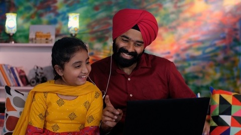 A cheerful Sikh Indian father-daughter wearing white earphones listening to music - favorite songs, playlist