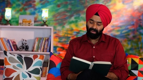 An attractive Indian man in his forties reading a book at home - an interesting book, a Sardarji, a Punjabi family