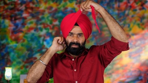  A handsome Punjabi Sardar fixing his red turban while wearing casual clothes - Punjabi culture and tradition