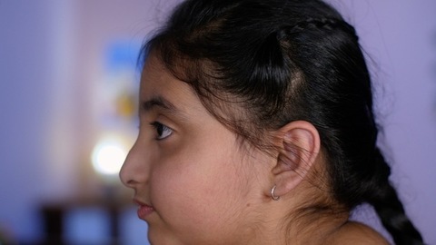 A middle-aged Punjabi man lovingly kissing his daughter on the forehead - a father-daughter moment, fatherly love