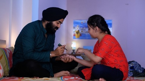 A North Indian Sardar wearing a turban is putting Mehendi on his daughter's hand - Henna, festival time, girl hobby